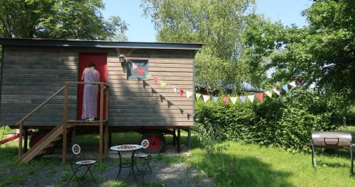 a woman standing at the door of a tiny house at Roulotte - Etat Nature in Magnières