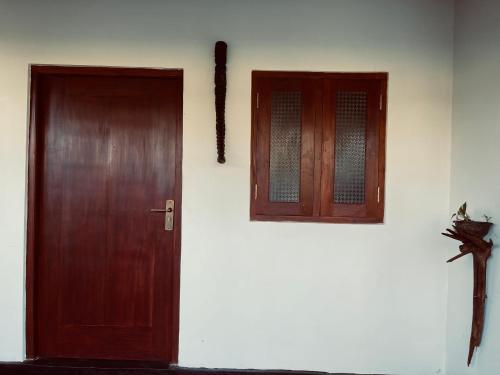 a wooden door and a window on a white wall at Lucky Lodge in Koggala