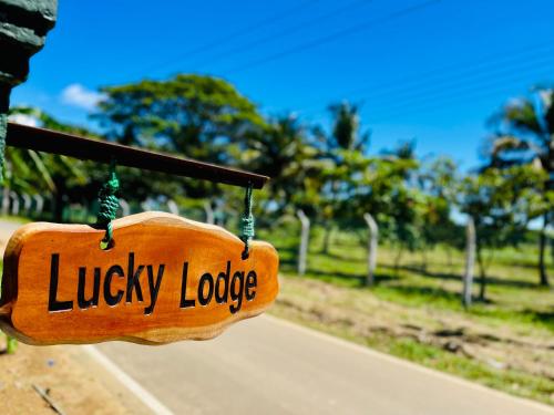 a sign that reads lucky lodge hanging on a pole at Lucky Lodge in Koggala