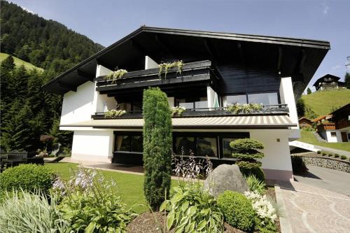 a white house with a black roof at Alpenpension Maderer in Gaschurn