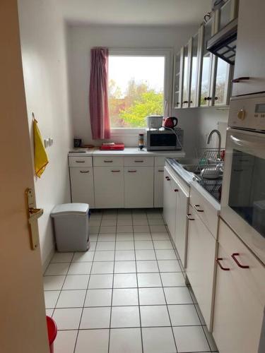 uma cozinha com armários brancos e uma janela em Logement entier : appartement ⸱ Chez Slimane em Massy