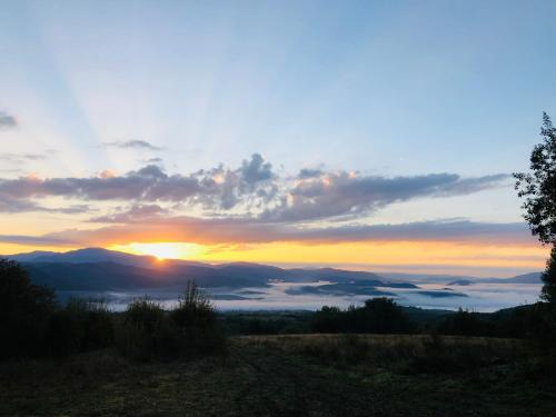 einen Sonnenuntergang mit Sonnenuntergang über den Bergen in der Unterkunft Еко Дім з СОЛОМИ in Solotschyn