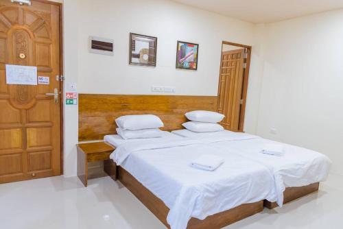 a bedroom with a bed with white sheets and a wooden door at MEHEL - Holiday Home - Mahibadhoo in Mahibadhoo