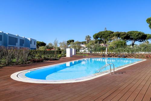 a large swimming pool on a wooden deck at Villa Central By Garvetur in Quarteira