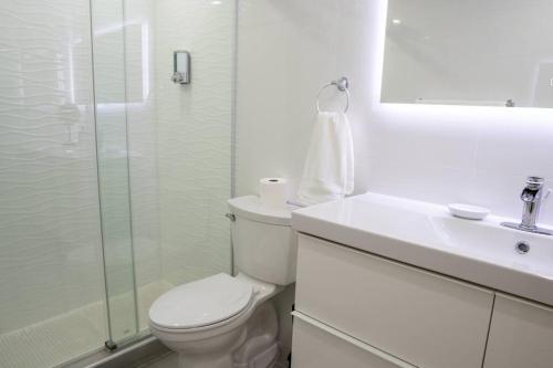 a white bathroom with a toilet and a sink at Hidden Gem @ Palmas Del Mar w/ View of Marina 999 in Humacao