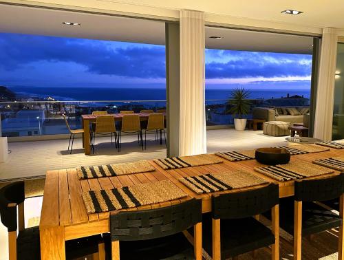 - une salle à manger avec une table et une vue sur l'océan dans l'établissement Villa Surf Vista - Praia da Areia Branca, à Lourinhã