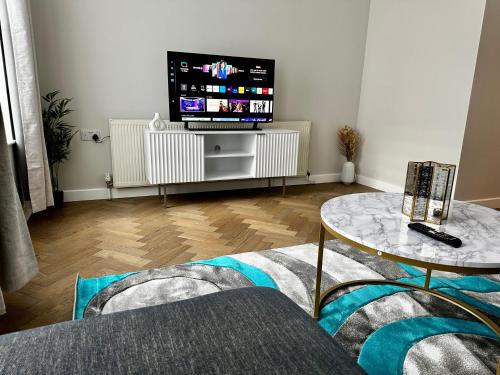 ein Wohnzimmer mit einem TV und einem Tisch in der Unterkunft Gero's One Bedroom apartment London NW8 in London