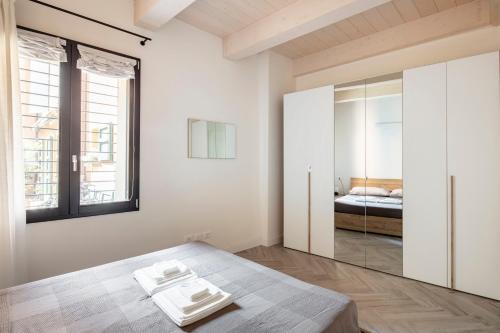 a white bedroom with a bed and a mirror at Piazza Savonarola 13 in Imola