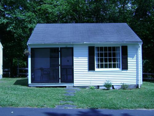 a small white shed with a porch on a lawn at Franconia Notch Motel in Lincoln