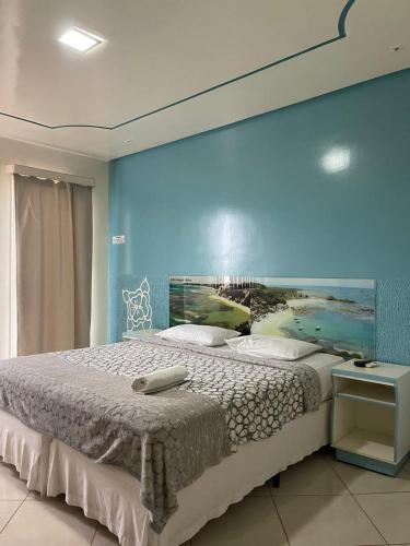 a bedroom with a large bed with a blue wall at HOTEL NOVA AMÉRICA in Teixeira de Freitas