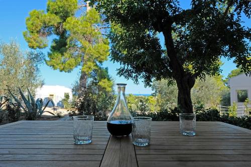 a bottle of wine and two glasses on a wooden table at Baia Degli Aranci Suite & Apartments in Vieste