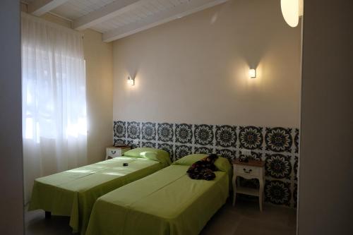 a bedroom with two beds with green sheets and a window at Baia Degli Aranci Suite & Apartments in Vieste