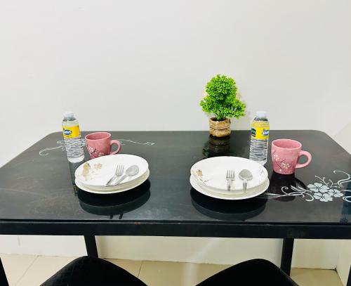 a black table with plates and forks and water at Sea Residences - Angel Alano in Manila