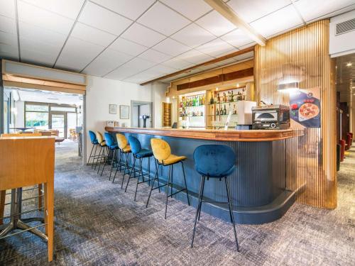 un bar avec tabourets bleus dans un restaurant dans l'établissement Novotel Macon Nord Autoroute du Soleil, à Mâcon