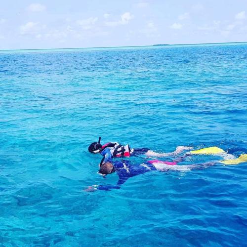 a person laying on a surfboard in the water at MEHEL - Holiday Home - Mahibadhoo in Mahibadhoo