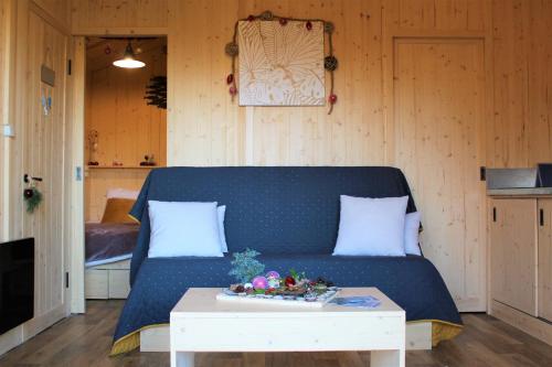 ein Wohnzimmer mit einem blauen Sofa und einem Tisch in der Unterkunft Tiny house - Cabane sur pilotis - Etat Nature in Magnières