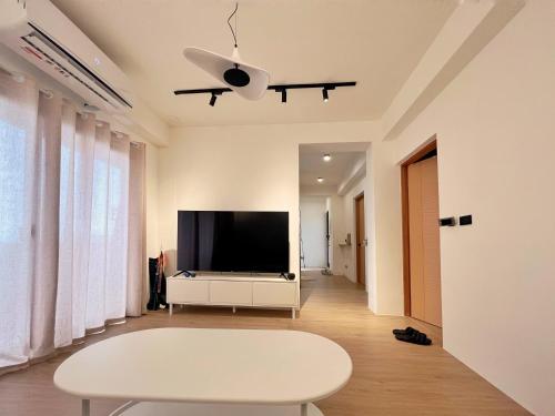a living room with a tv and a white table at Sunset Hostel in Lanyu