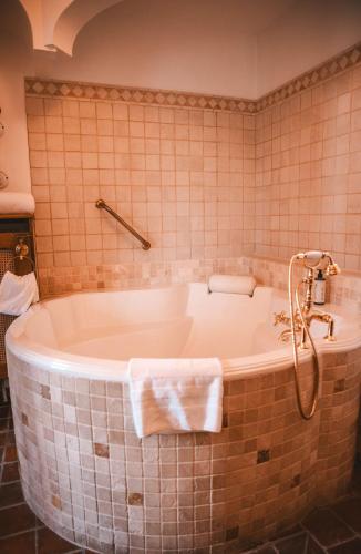 a bath tub in a tiled bathroom with a shower at Les Violettes Hotel & Spa in Jungholtz