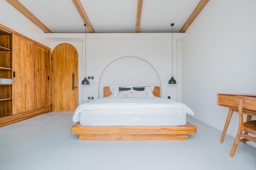 - une chambre avec un lit blanc et un bureau en bois dans l'établissement Babali 希腊风格别墅, à Canggu
