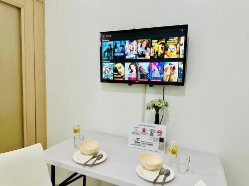 a table with two cups and a tv on the wall at Sea Residences Tower F Angel in Manila