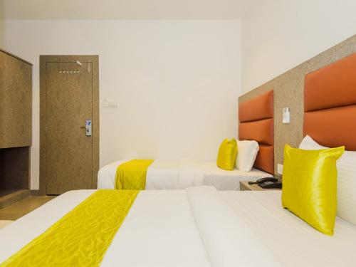 a hotel room with two beds with yellow pillows at Hotel Zillion Executive Near US Consulate Bandra Kurla Complex Mumbai Near Mumbai Airport Mumbai in Mumbai