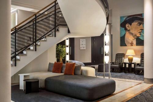 a living room with a couch and a staircase at Vienna House by Wyndham Remarque Osnabrück in Osnabrück