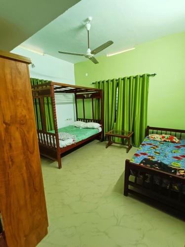 - une chambre avec 2 lits superposés et des rideaux verts dans l'établissement Bamboo garden, à Varkala
