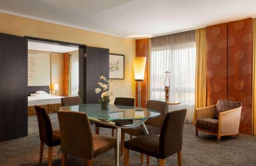 a room with a table and chairs and a bedroom at Vienna House by Wyndham Remarque Osnabrück in Osnabrück