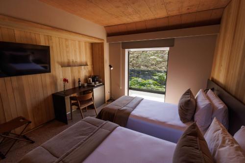 a hotel room with two beds and a desk and a window at Hualta Hotel Mendoza, Curio Collection by Hilton in Mendoza