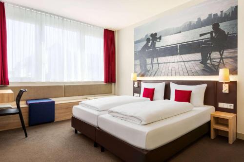 a hotel room with two beds and a window at Vienna House Easy by Wyndham München in Munich