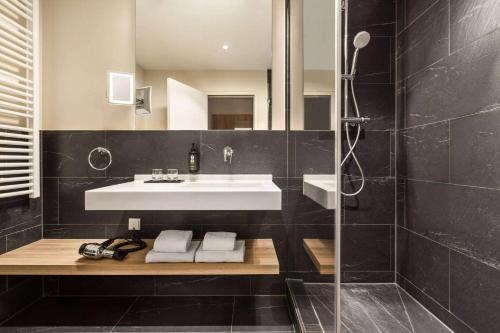a bathroom with a sink and a shower with a mirror at Vienna House Easy by Wyndham München in Munich
