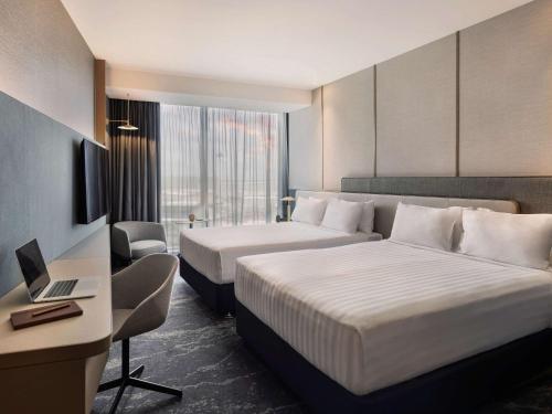 a hotel room with two beds and a desk at Pullman Auckland Airport in Auckland