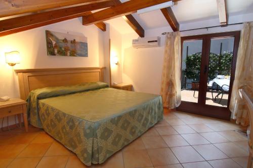 Hotel Due Torri في أَجيرولا: غرفة نوم بسرير وباب للباحة
