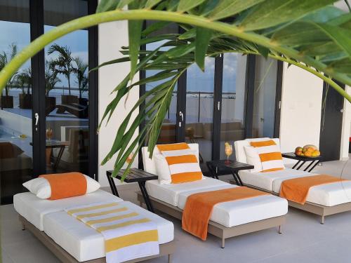 three beds with orange and white pillows on a balcony at Villa Regatta in Hato