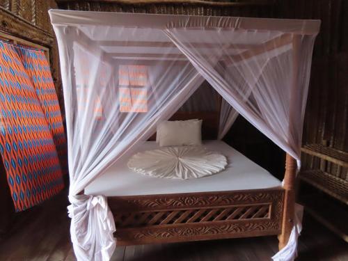 a bed with a canopy with white sheets and pillows at Drifters Zanzibar in Paje