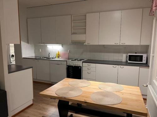a kitchen with white cabinets and a wooden table at Apartment Korsholma2 in Vaasa