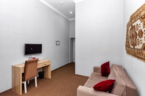 a living room with a couch and a desk and a television at Nizami by La Casa Hotel in Baku