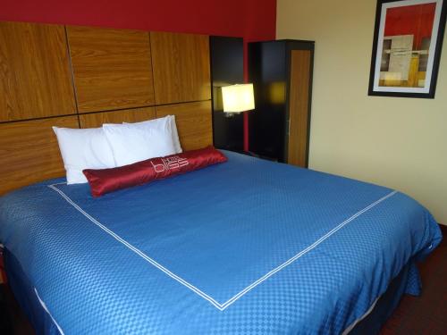 a large blue bed with a red pillow on it at Hotel Bliss - Brooklyn in Brooklyn