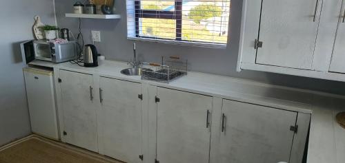 a kitchen with white cabinets and a sink and a window at View on the Bay 7 Pinta Crescent in St Helena Bay