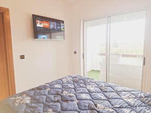 a bedroom with a bed with a tv on the wall at Marina golf studio in Asilah