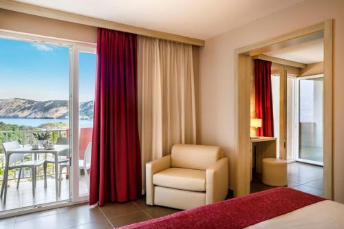 a bedroom with a bed and a chair and a balcony at San Marino Resort in Lopar