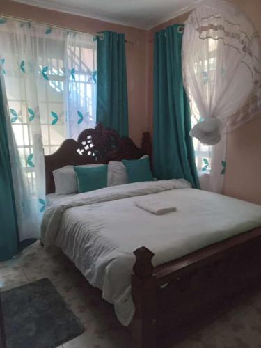 1 dormitorio con 1 cama grande y cortinas verdes en LAURAPA home's, en Kisumu