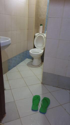 baño con aseo y zapatillas verdes en el suelo en LAURAPA home's, en Kisumu