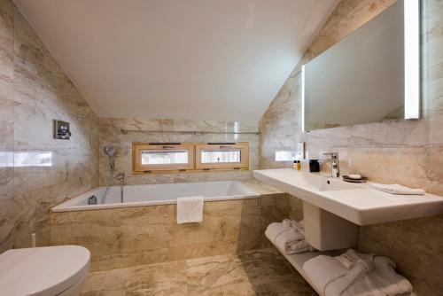 a bathroom with a tub and a sink and a toilet at Hotel du Lac in Villars-sur-Ollon