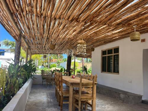 un patio con pérgola de madera, mesa y sillas en Villa Upendo Paje en Paje