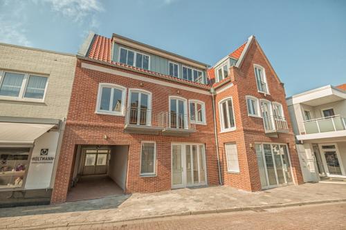 a red brick building with windows on a street at MeerBlickD21 Residenzen in Norderney