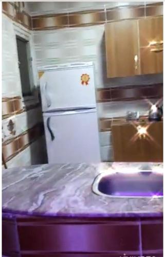 uma cozinha com um frigorífico branco e uma bancada roxa em مفروش مصر الجديده no Cairo