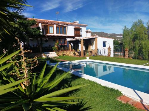 a villa with a swimming pool in front of a house at Paraje El Pozo in Málaga