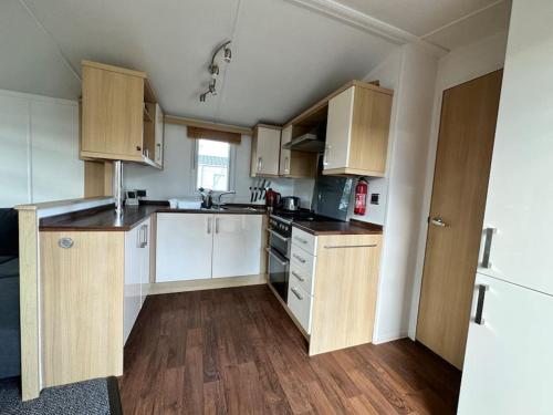 uma pequena cozinha com armários brancos e pisos em madeira em Beautiful newly decorated cabin em Great Billing