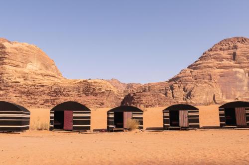 a building in the desert with mountains in the background at Bedouin Tribe Camp Wadi Rum in Wadi Rum
